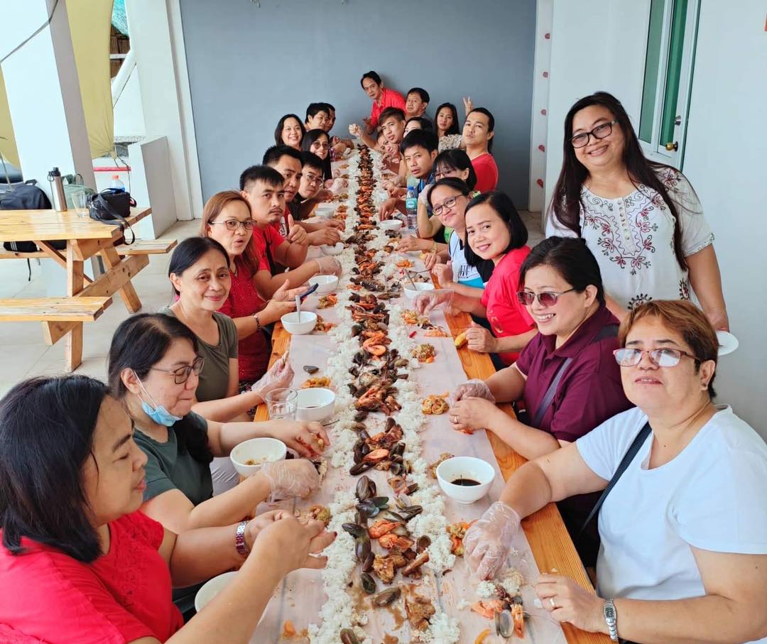 big group of people enjoying eating a boodle fight at the escape hotel san juan